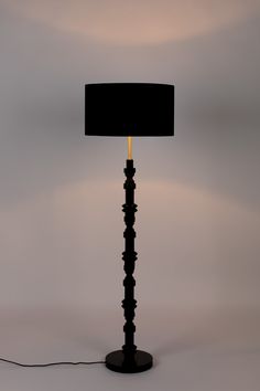 a floor lamp with a black shade on the base and a yellow light at the end