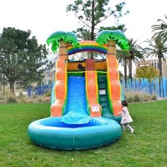 an inflatable water slide with palm trees on it and a toddler playing inside