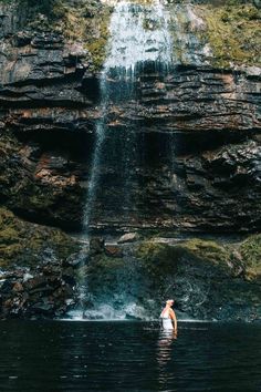 a person standing in the water under a waterfall