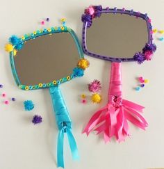 two mirrors with pom poms on them and one has a blue ribbon around it