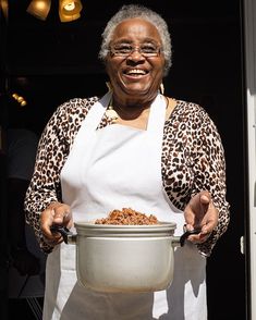 an older woman is holding a bowl of food