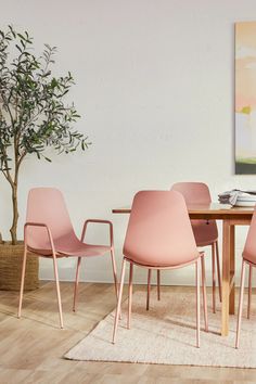 a dining room table with pink chairs and a potted plant