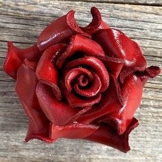 a red rose sitting on top of a wooden table