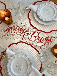 the table is set with white and red plates, silverware, candles and napkins