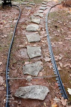 a set of train tracks in the woods with rocks on each side and a bench at the end