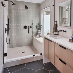 a bathroom with a walk in shower next to a white sink and wooden cabinetry