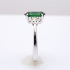 This oval cut Tsavorite Garnet, set at the center of this ring steals the show. It’s rich green, has been highlighted by the perfectly matched round brilliant diamonds that rest on either side of the center stone. Eye clean and large in size, this 2.13 carat stone is a rare gem. Set in 18K white gold, this ring is just the right combination grace and beauty. Order online info@jupitergem.com Oval Tsavorite Diamond Ring For Formal Occasions, Green Halo Ring With Brilliant Round Cut, Gia Certified Oval Green Diamond Ring, Brilliant Cut Oval Diamond Ring With Tsavorite, Classic Green Halo Ring With Round Cut, Green Oval Diamond Halo Ring, Oval Green Emerald Ring With Center Stone, Oval Green Diamond Halo Ring, Classic Green Halo Ring Round Cut