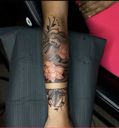 a woman's arm with a snake and flowers tattoo on her left forearm, sitting in a chair