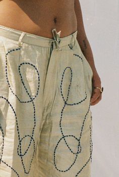 a person standing on the beach with their back to the camera, wearing white shorts