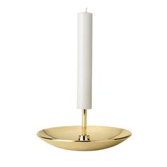 a white candle sitting on top of a gold plate