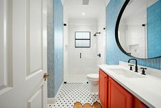 a bathroom with blue and white tiles on the walls, red cabinetry, and black and white flooring