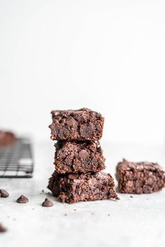 three chocolate brownies stacked on top of each other next to a cooling rack filled with chocolate chips