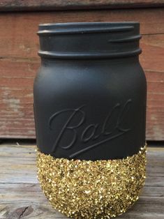 a black and gold mason jar sitting on top of a wooden table