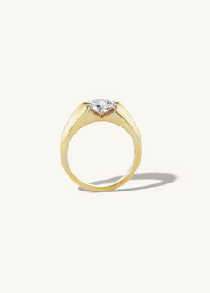 a yellow gold ring with a heart shaped diamond in the center, on a white background