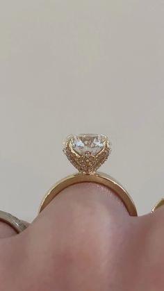 a person's hand holding an engagement ring with a large diamond in the middle