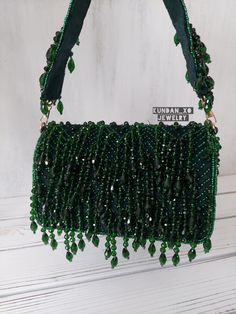 Our best seller for holiday parties, weddings and special occasions!  BREATH TAKING designer clutch with heavy hand embroidery is sure to turn heads! Elegantly embellished with crystal bead work in beautiful tones on a matte EMERALD GREEN velvet base. Fully stitched hand embellisments all over. Indo-western handbag comes with custom crystal beaded top handle which is detachable so can be worn multiple ways! GOLD hardware details. PERFECT clutch sized to fit  phones and accessories in style! Flap Emerald Green Purse, Green Embellished Evening Bag For Wedding, Green Embellished Wedding Bags, Green Beaded Evening Bag For Party, Green Embellished Wedding Bag, Green Beaded Bag For Party, Green Beaded Bags For Parties, Evening Green Clutch With Handwork, Traditional Embellished Green Bag