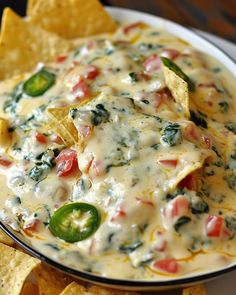 a white plate topped with nachos covered in cheese and toppings next to tortilla chips