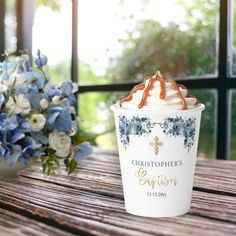 a cup with whipped cream and blue flowers in the background