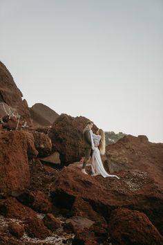 a man and woman are standing on some rocks