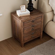 a small wooden table with two drawers and a flower on it next to a couch