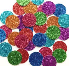 multicolored glitter confetti circles are scattered on a white surface, with one circle in the center