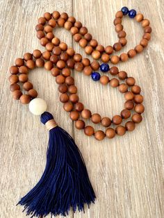 Sandalwood is a fragrant and soothing bead that is very calming to the mind. This mala is made up of mostly sandalwood, with Lapis Lazuli markers at the 27th and 54th positions. A moonstone guru bead sits on top of the handmade navy silk tassel. Such a neutral and earthy mala that feels great to wear and use for meditation. 8mm Sandalwood8mm Lapis Lazuli12mm MoonstoneNavy CordSilk Tassel Each mala I make comes shipped in a beautiful Mala Bag for safe keeping. Properties of the Stones in this Mal Spiritual Natural Jewelry For Meditation, Natural Spiritual Jewelry For Meditation, Natural Wooden Beads Necklace For Meditation, Handmade Wooden Jewelry For Meditation, Spiritual Style Natural Beaded Necklace Gift, Spiritual Natural Beaded Necklaces As Gift, Spiritual Natural Beaded Necklace Gift, Holistic Healing Mala With Wooden Beads, Wooden Round Beads Jewelry For Meditation