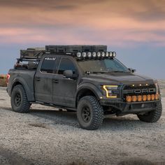 a gray truck with lights on driving through the desert