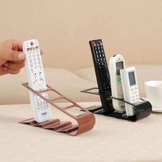 a hand holding a remote control next to two different types of remote controls on a table