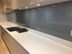 an empty kitchen with white counter tops and gray cabinets