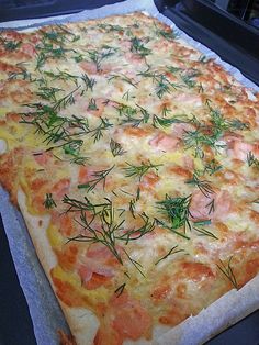 a square pizza with cheese and tomatoes on it sitting on top of a baking sheet