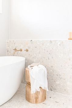 a white bath tub sitting next to a wooden stool