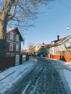 a street with snow on the ground and houses in the background