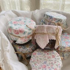 four small boxes are sitting in a basket with flowers and leaves on them, tied to twine