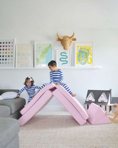 two children playing in a playroom with pink furniture and artwork on the wall behind them