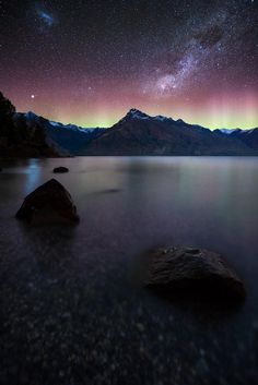 the night sky is filled with stars and aurora lights over lake wakatu, new zealand