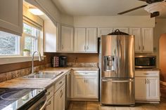 a kitchen with white cabinets and stainless steel appliances