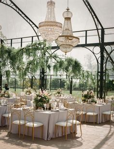 the tables are set with white linens and chandeliers hanging from the ceiling