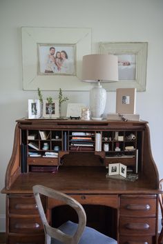 a desk with a chair, lamp and pictures on the wall