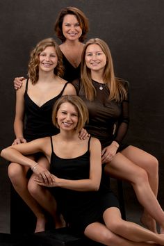 three women in black dresses posing for a photo with their arms around one woman's shoulders