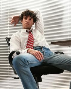 a man sitting in an office chair with his feet on the desk and arms behind his head