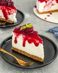 two black plates topped with cheesecake covered in cherries and cranberry sauce