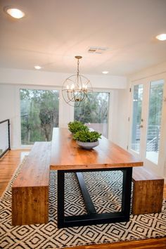 a dining room table with a bowl on top of it and lights hanging from the ceiling