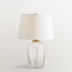 a glass table lamp with a white shade on it's base and a gold - plated metal base