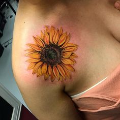 a sunflower tattoo on the side of a woman's breast, with yellow petals