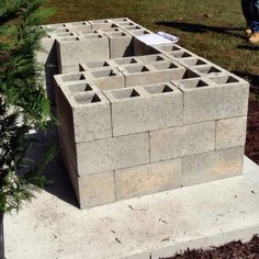 a cement block structure sitting in the middle of a yard with people walking around it