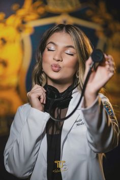 a woman wearing a white jacket and black tie holding a microphone in front of her face