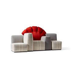 a red pillow sitting on top of a gray couch next to two white chairs and a table