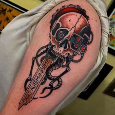 a man's arm with a skull holding a knife and some scissors on it