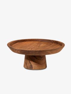 a wooden bowl sitting on top of a white surface with no one around it,