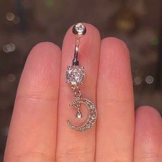 a person's hand holding a belly ring with a crescent and star design on it